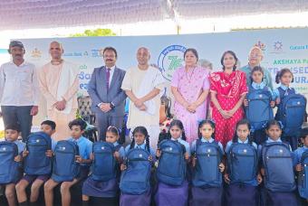 The beneficiaries are happy to receive school bags from the guests at the kitchen inaugural ceremony.