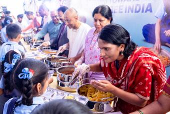 Smt Latha kumari Kumari interacts with one beneficiary while serving meals to them.