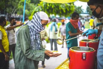 A hungry person receives his food from the team.